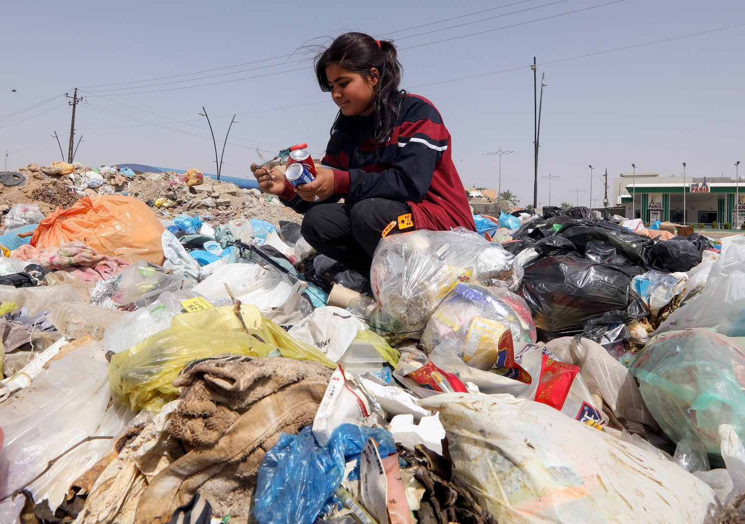 Sahar Shaaban, 11, an Iraqi girl who provides for her family, collects cans from a garbage area in Kirkuk, Iraq, April 21, 2021.